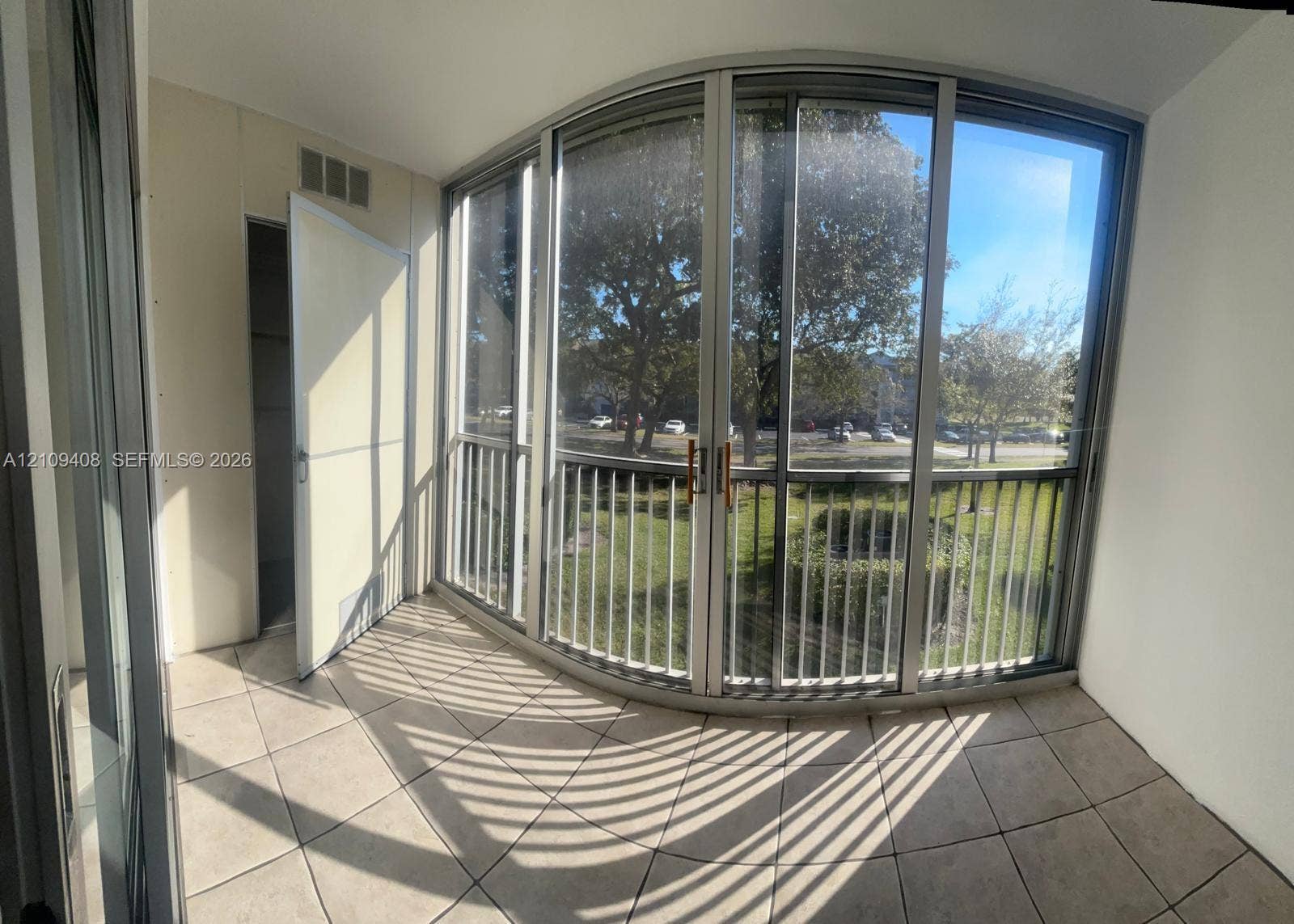 12600 SW 5th Court, #208L, Pembroke Pines, Pembroke Pines, FL 33027 Enclosed balcony featuring tile flooring, a curved wall of floor-to-ceiling windows, and vertical metal railings