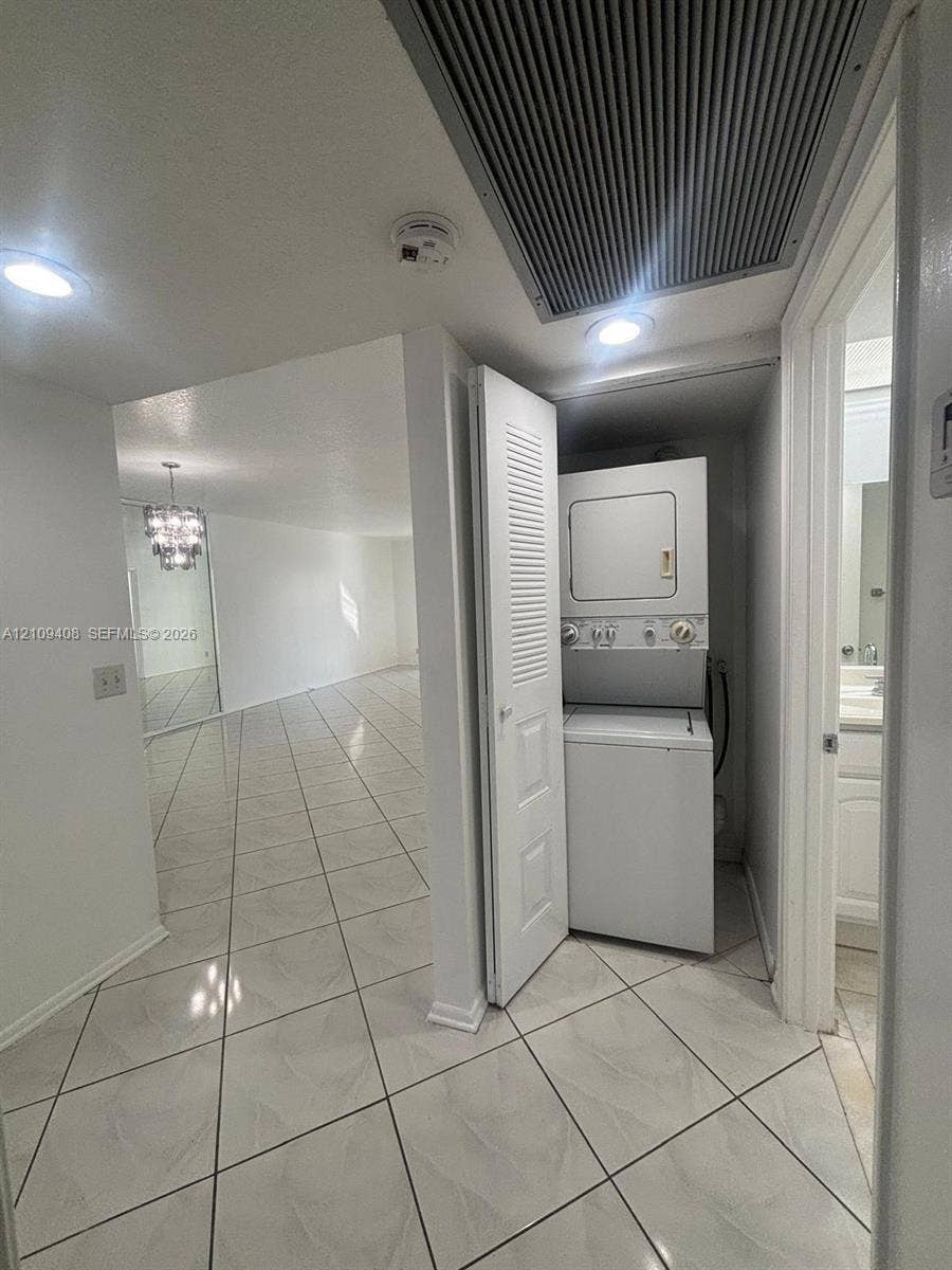 12600 SW 5th Court, #208L, Pembroke Pines, Pembroke Pines, FL 33027 Laundry area featuring a stacked washer and dryer unit enclosed by louvered bi-fold doors, complemented by ceramic tile flooring and recessed lighting