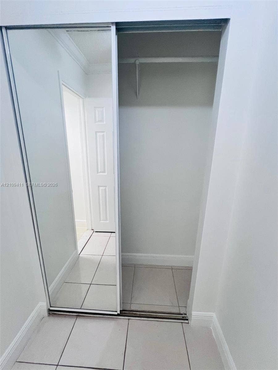 Sliding mirrored closet doors, large-format tile flooring, and a built-in garment rod