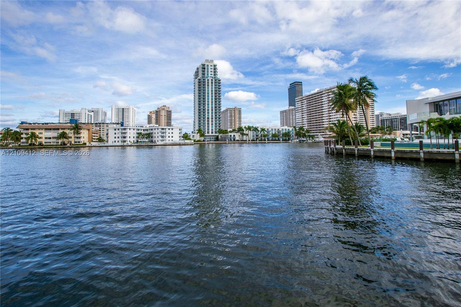 137 Golden Isles Drive, #408, Hallandale Beach, FL 33009 Waterfront location featuring a concrete bulkhead, paved grounds, and palm tree landscaping