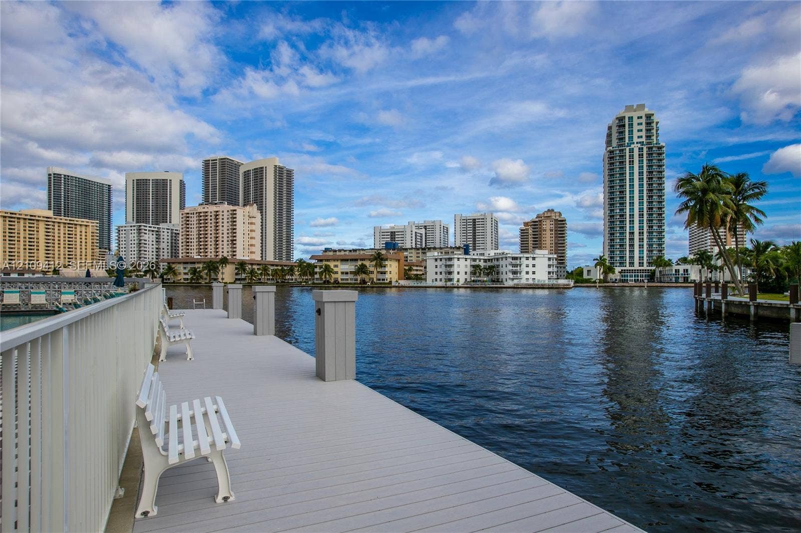 137 Golden Isles Drive, #408, Hallandale Beach, FL 33009 Waterfront dock featuring composite decking, white railings, and built-in benches