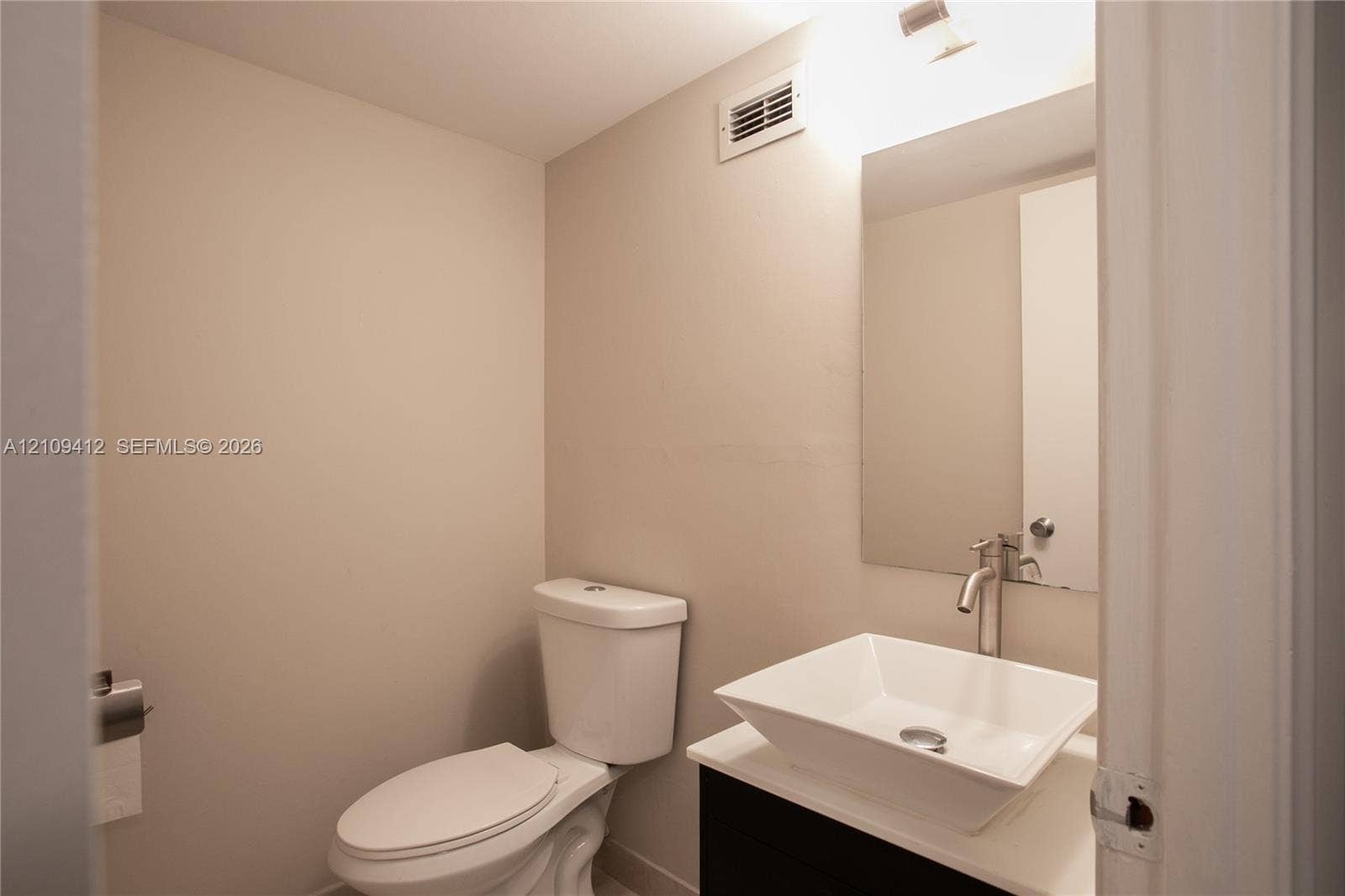 137 Golden Isles Drive, #408, Hallandale Beach, FL 33009 Modern vanity featuring a rectangular vessel sink with a wall-mounted faucet, crisp countertop, and frameless mirror