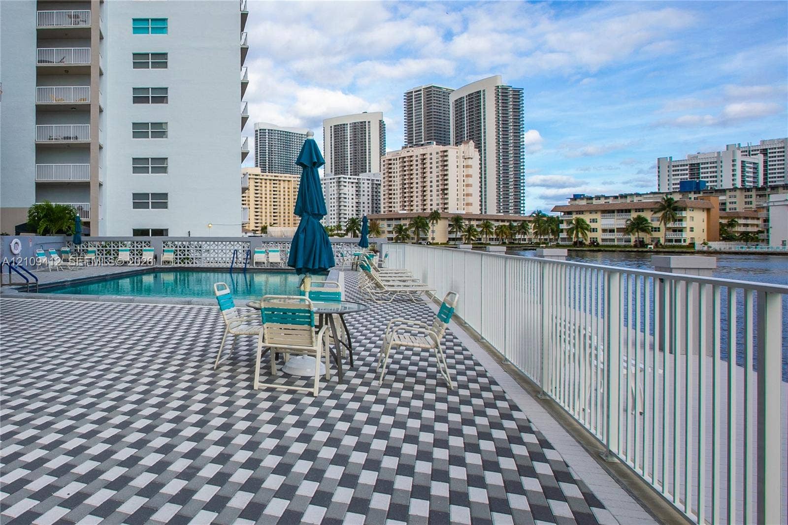 137 Golden Isles Drive, #408, Hallandale Beach, FL 33009 Pool deck featuring patterned paver surfacing, rectangular swimming pool, and metal perimeter railing