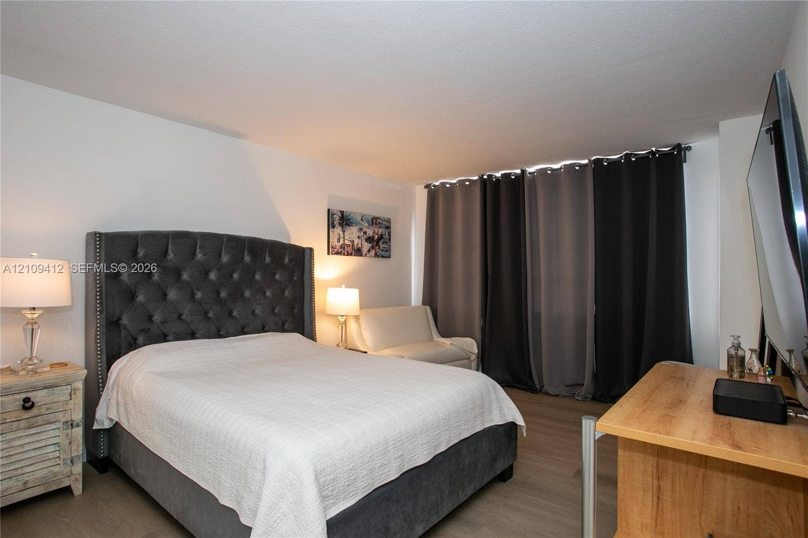 137 Golden Isles Drive, #408, Hallandale Beach, FL 33009 Neutral-toned living space featuring light-toned wood-finish flooring and full-height wall-to-wall drapery