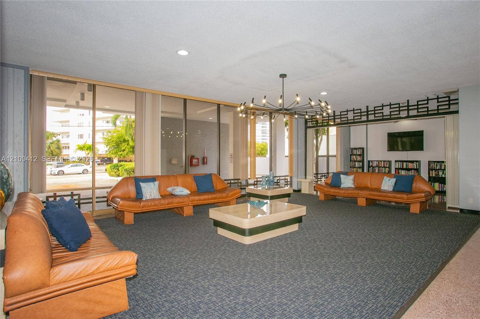 137 Golden Isles Drive, #408, Hallandale Beach, FL 33009 Common area featuring floor-to-ceiling glass windows, a decorative geometric lattice screen, a multi-arm chandelier, and wall-to-wall carpeting