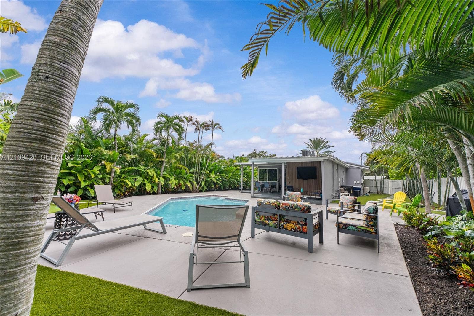 1955 Thomas Street, Hollywood, FL 33020 Outdoor living area featuring a swimming pool, concrete deck, covered patio, and established palm trees