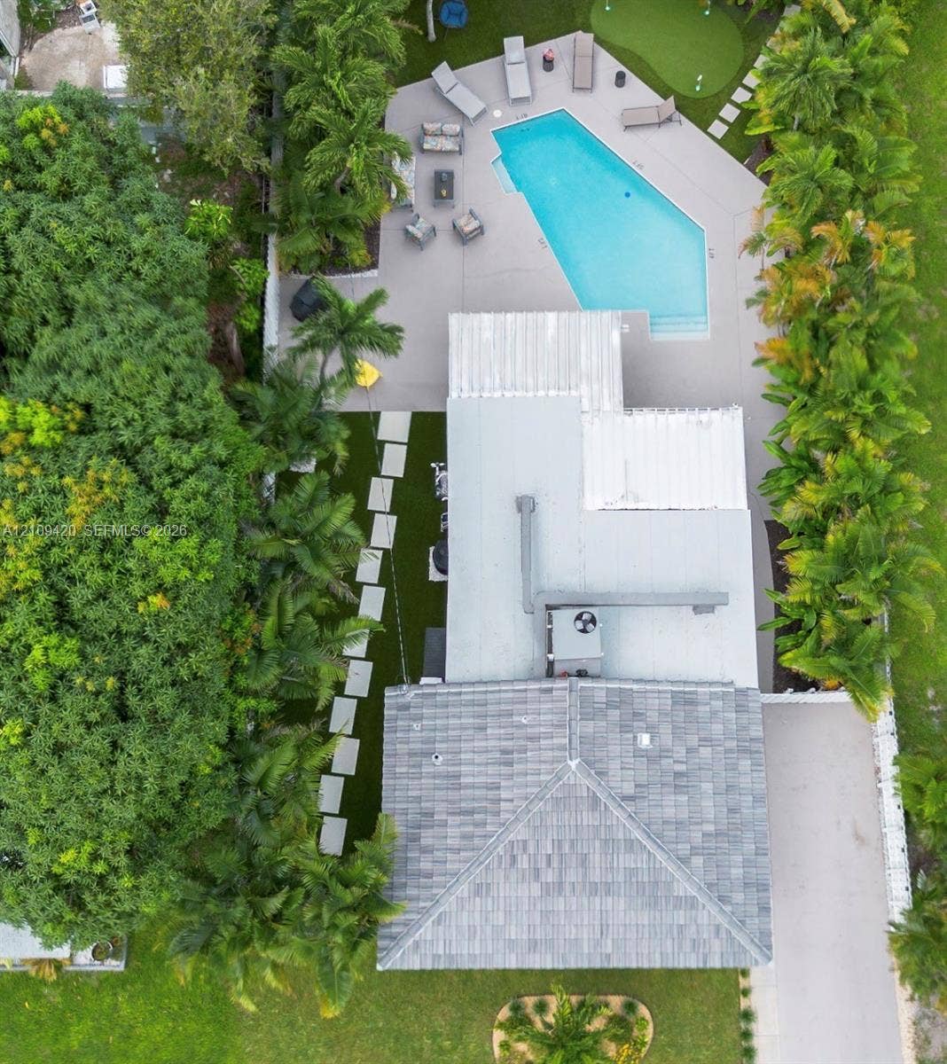 1955 Thomas Street, Hollywood, FL 33020 Aerial perspective of a rear yard featuring a pool, synthetic putting green, paved deck, and concrete paver walkway through a landscaped lawn