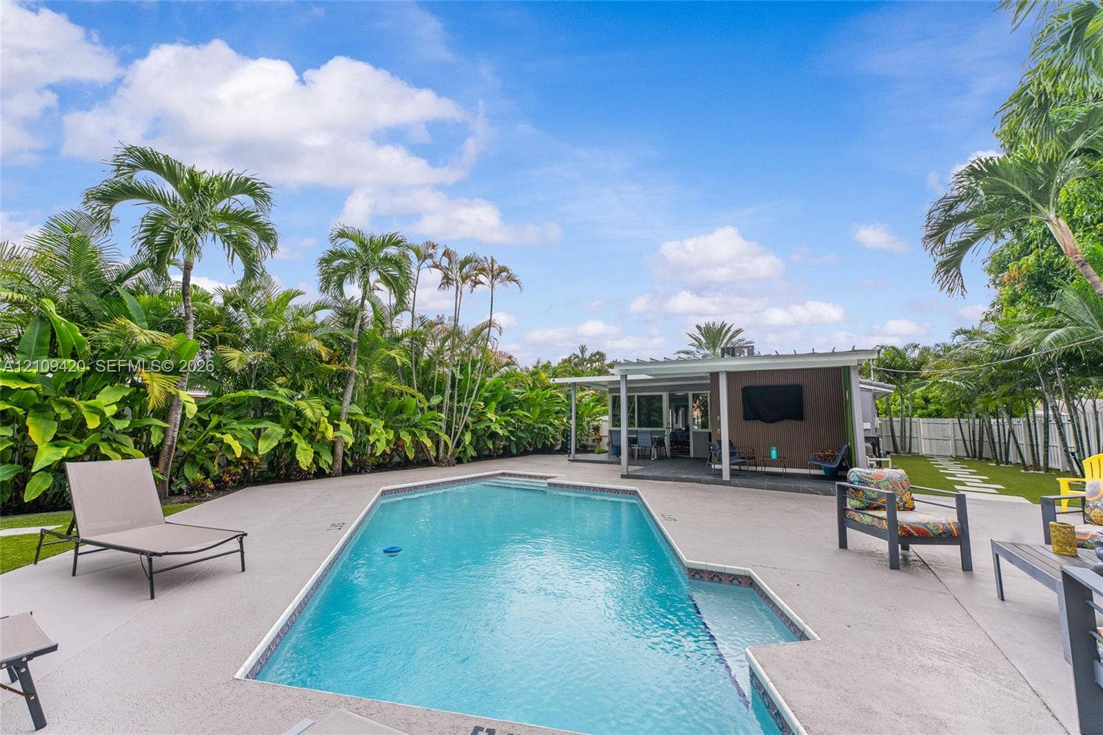 1955 Thomas Street, Hollywood, FL 33020 Backyard featuring an in-ground swimming pool, concrete pool deck, covered patio with structural support columns, and mature tropical landscaping