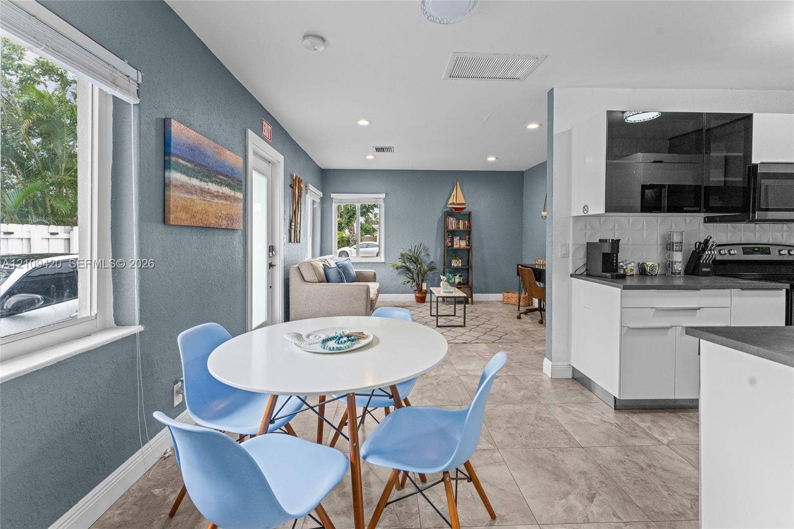 1955 Thomas Street, Hollywood, FL 33020 Kitchen featuring white cabinetry, dark countertops, a textured tile backsplash, and tile flooring, enhanced by recessed lighting
