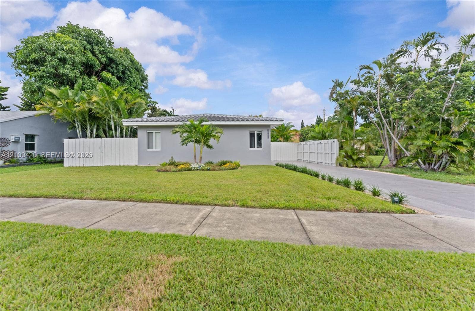 1955 Thomas Street, Hollywood, FL 33020 Single-story exterior featuring a gray stucco facade, a concrete tile roof, a manicured lawn, and perimeter privacy fencing