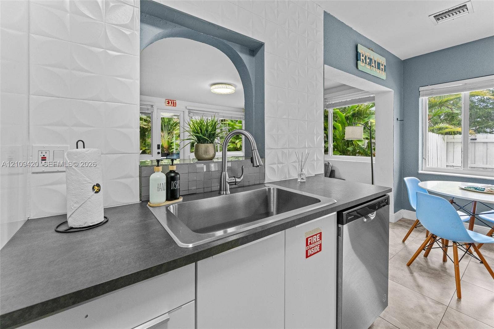 1955 Thomas Street, Hollywood, FL 33020 Kitchen featuring stainless steel undermount sink, gooseneck faucet, dark composite countertops, three-dimensional geometric tile backsplash, and stainless steel dishwasher