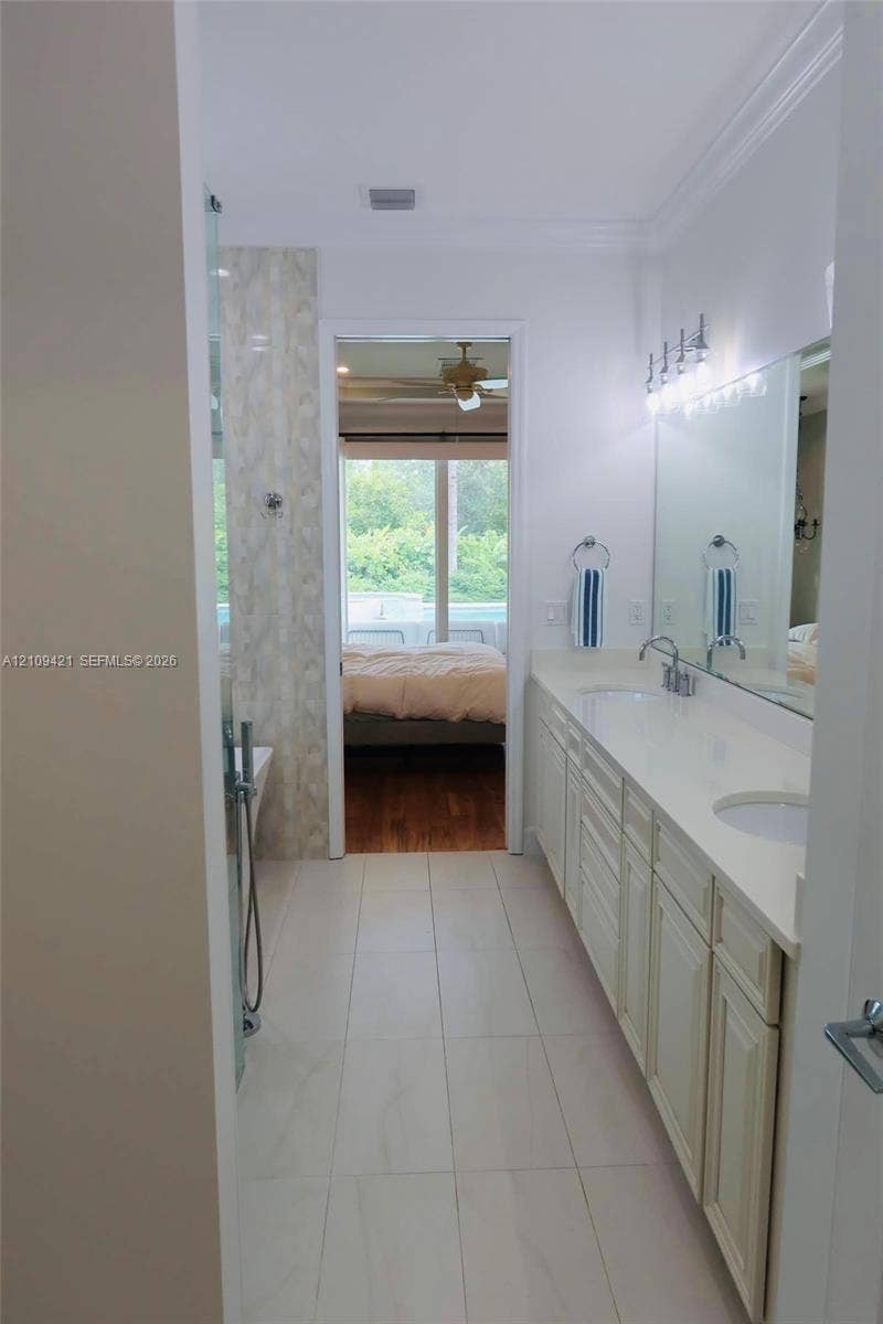 Bathroom featuring dual-sink vanity with light-tone cabinetry, quartz countertop, full-width wall mirror, and large-format tile flooring