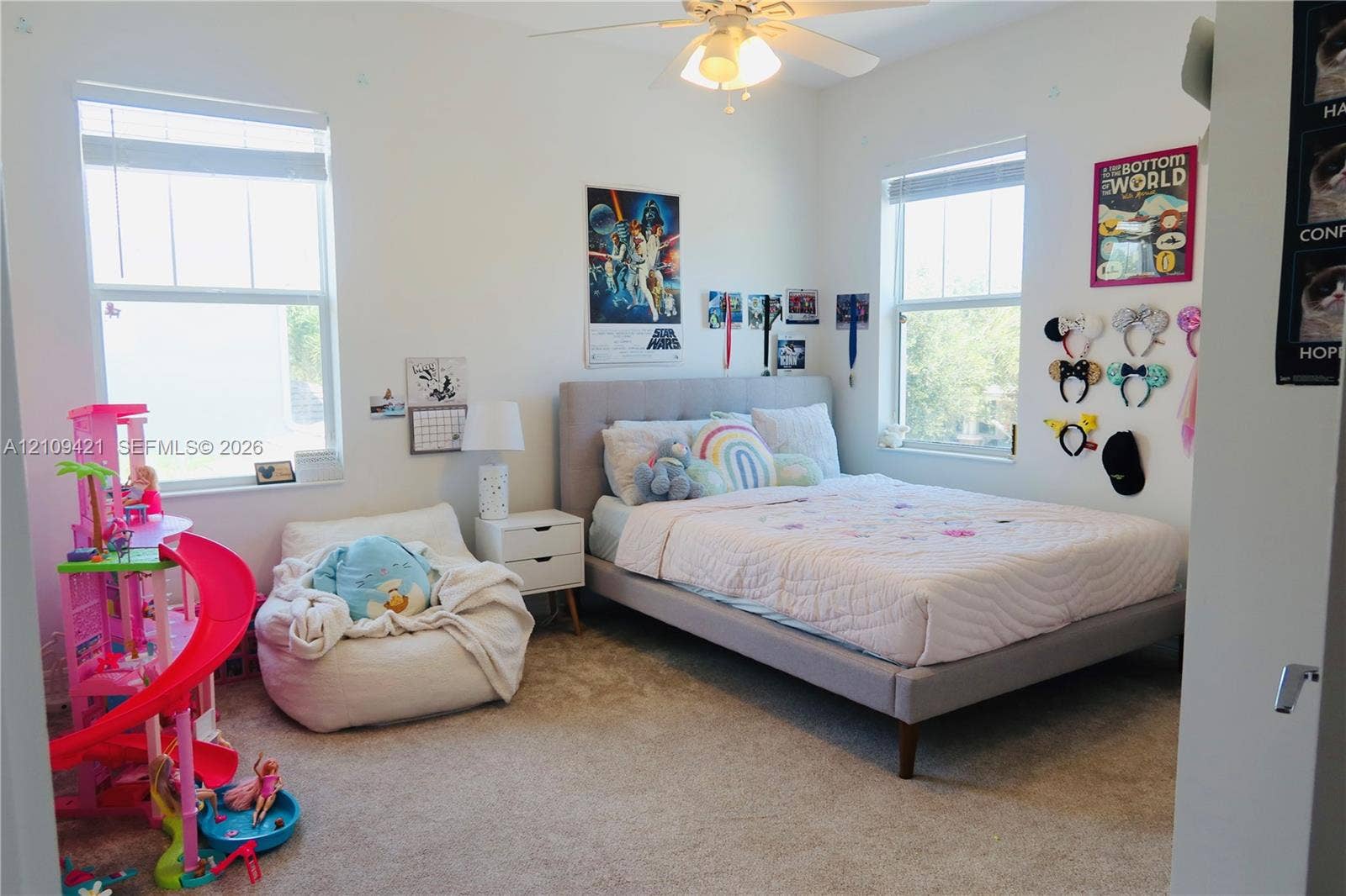 Bedroom featuring neutral carpeted flooring, dual windows with blinds, and a ceiling fan with integrated lighting