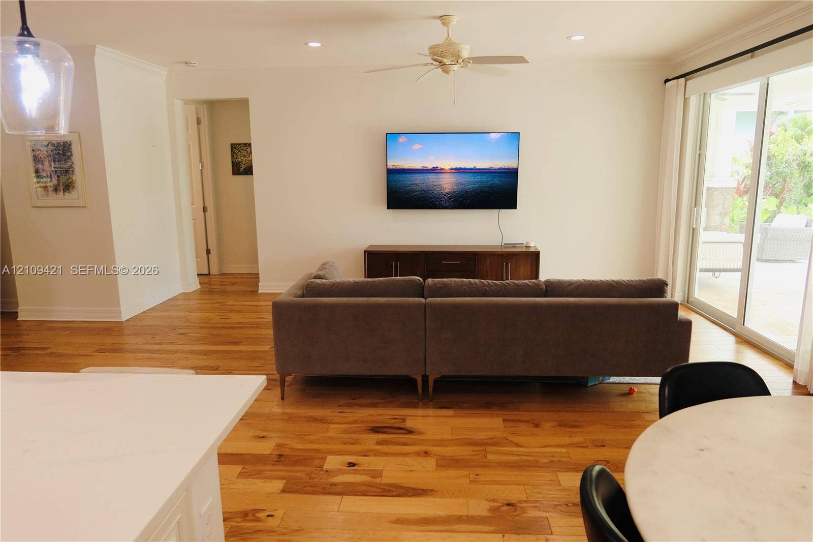 Living area featuring wood-finish flooring, ceiling-mounted paddle fan, recessed lighting, and expansive glass sliding doors