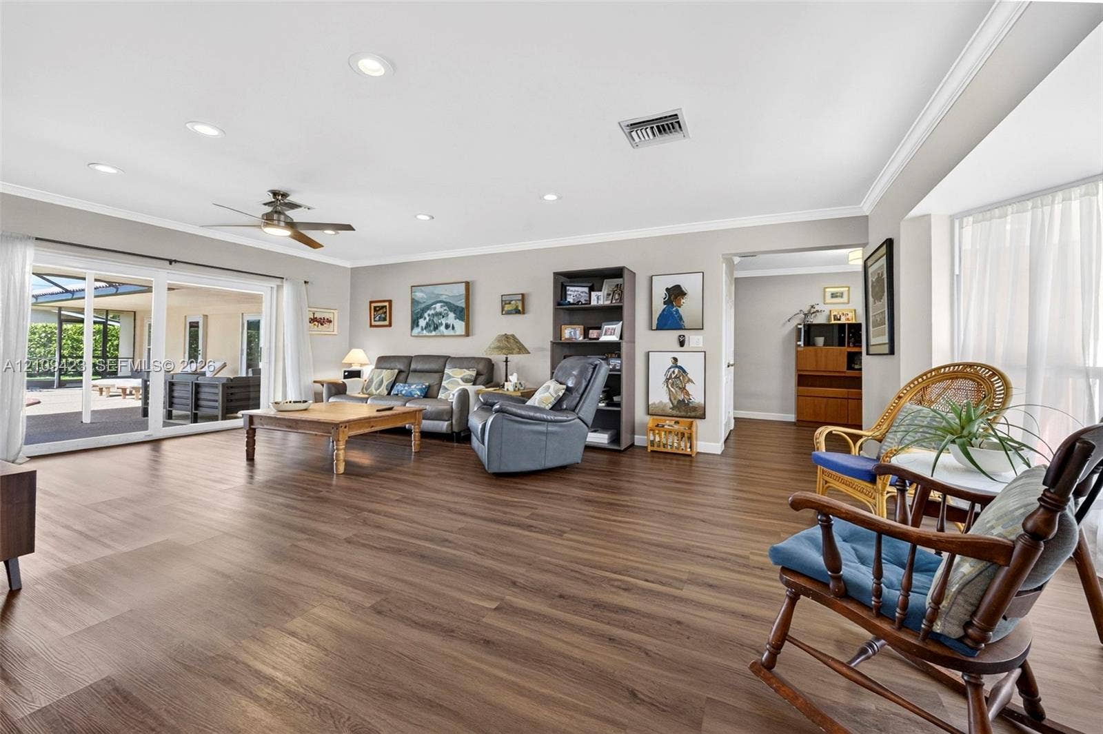 Open-concept interior featuring wood-finish flooring, recessed lighting, crown molding, and sliding glass doors