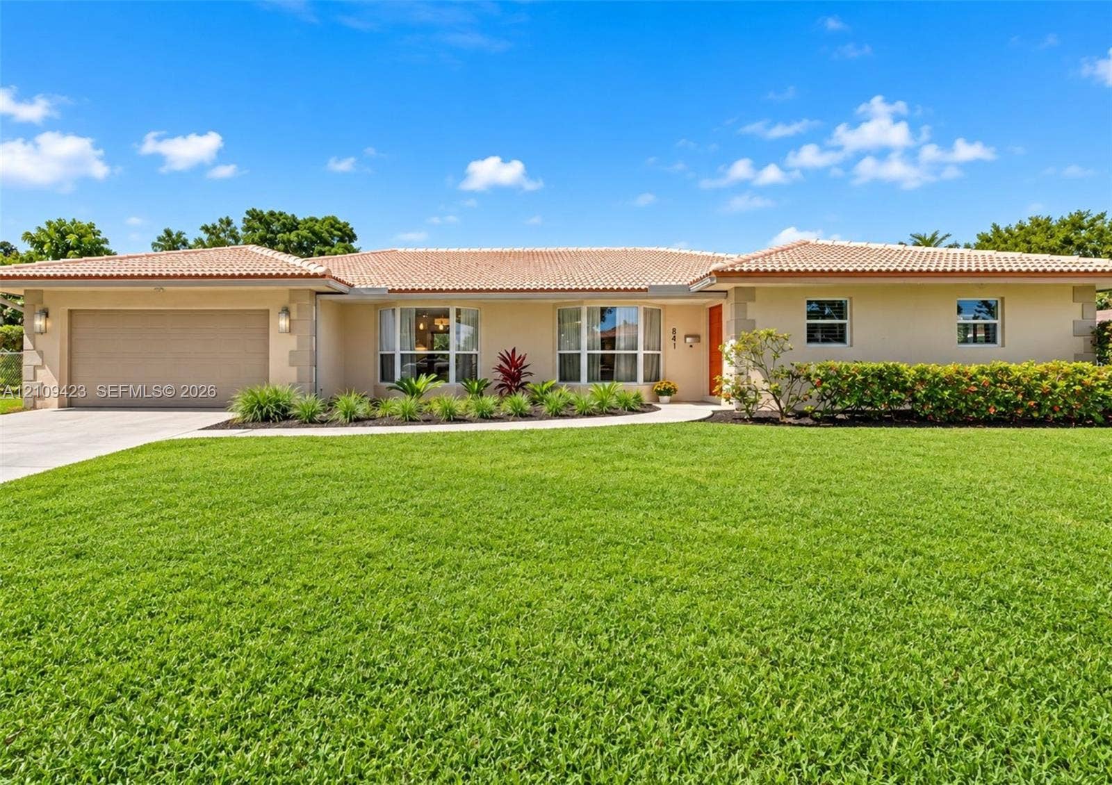 Single-story residence featuring a tile roof, stucco exterior, two-car garage, and manicured landscaping