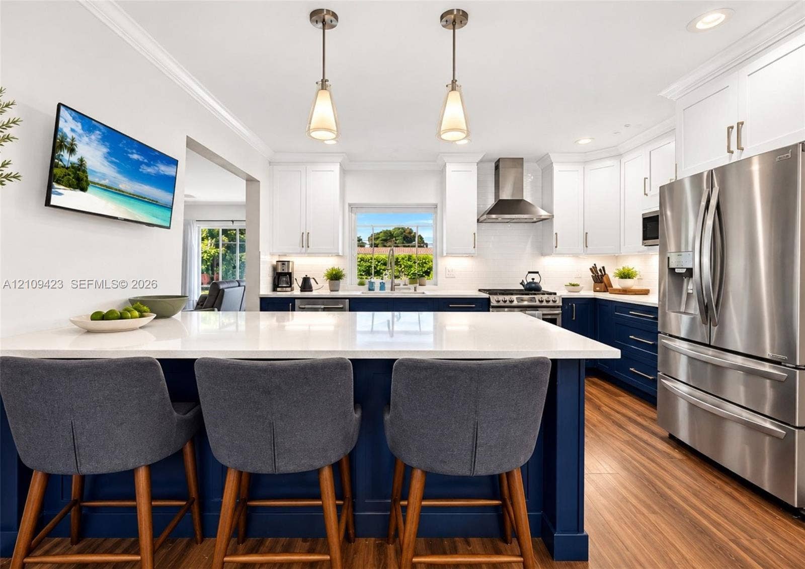 Kitchen featuring two-tone cabinetry, quartz countertops, stainless steel appliances, wood-finish flooring, and dual pendant lighting