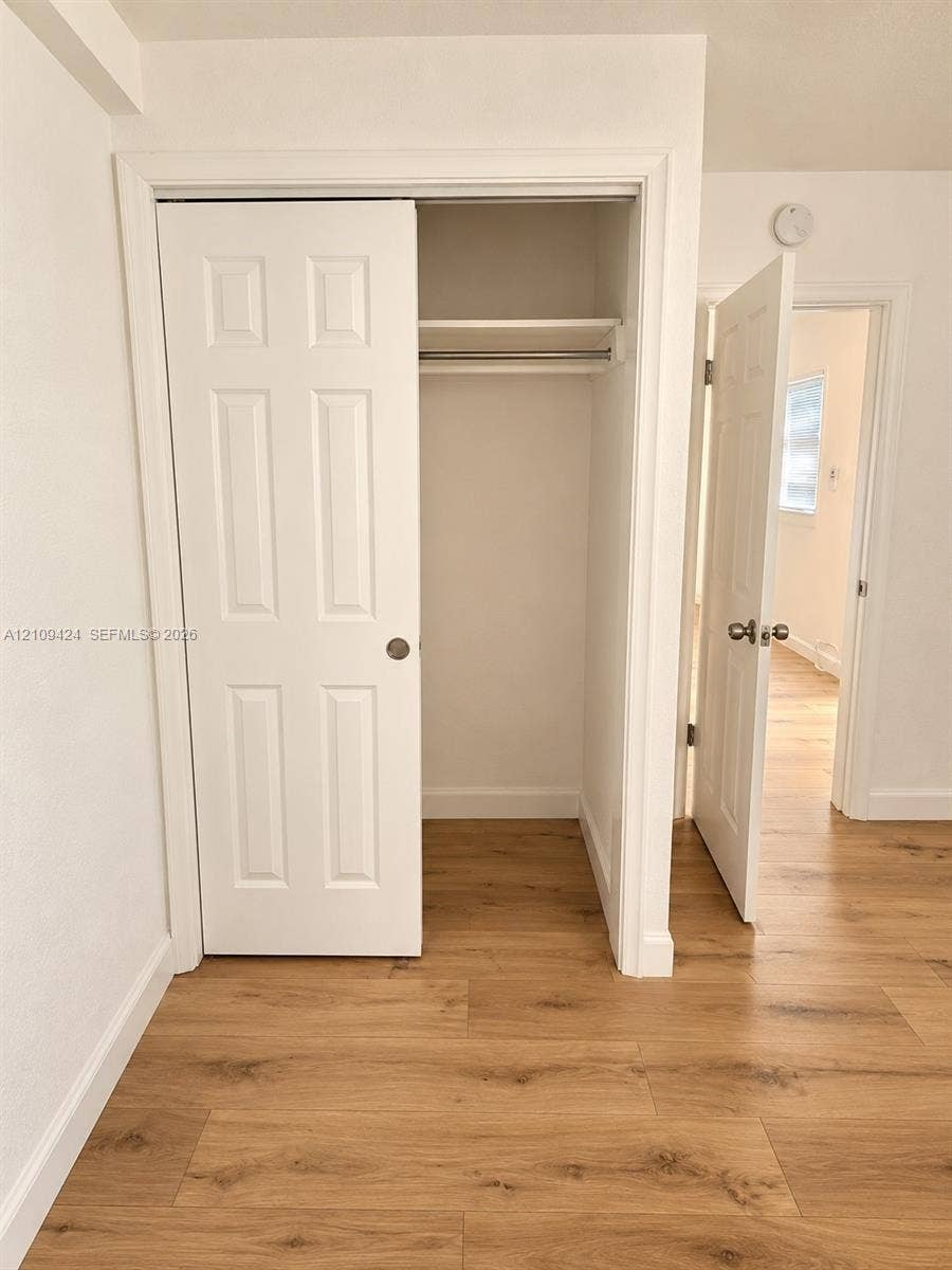 840 NW 10th Street, #5, Hallandale Beach, Hallandale Beach, FL 33009 Closet featuring a six-panel door and built-in shelving, complemented by wood-finish flooring