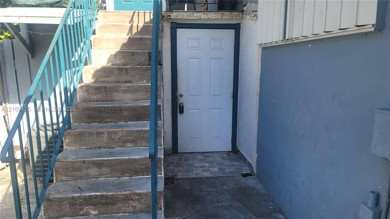 615 NW 25th Court, #B, Miami, Miami, FL 33125 Exterior entry featuring concrete stairs with a metal railing and a multi-panel door with stone-tile flooring at the threshold