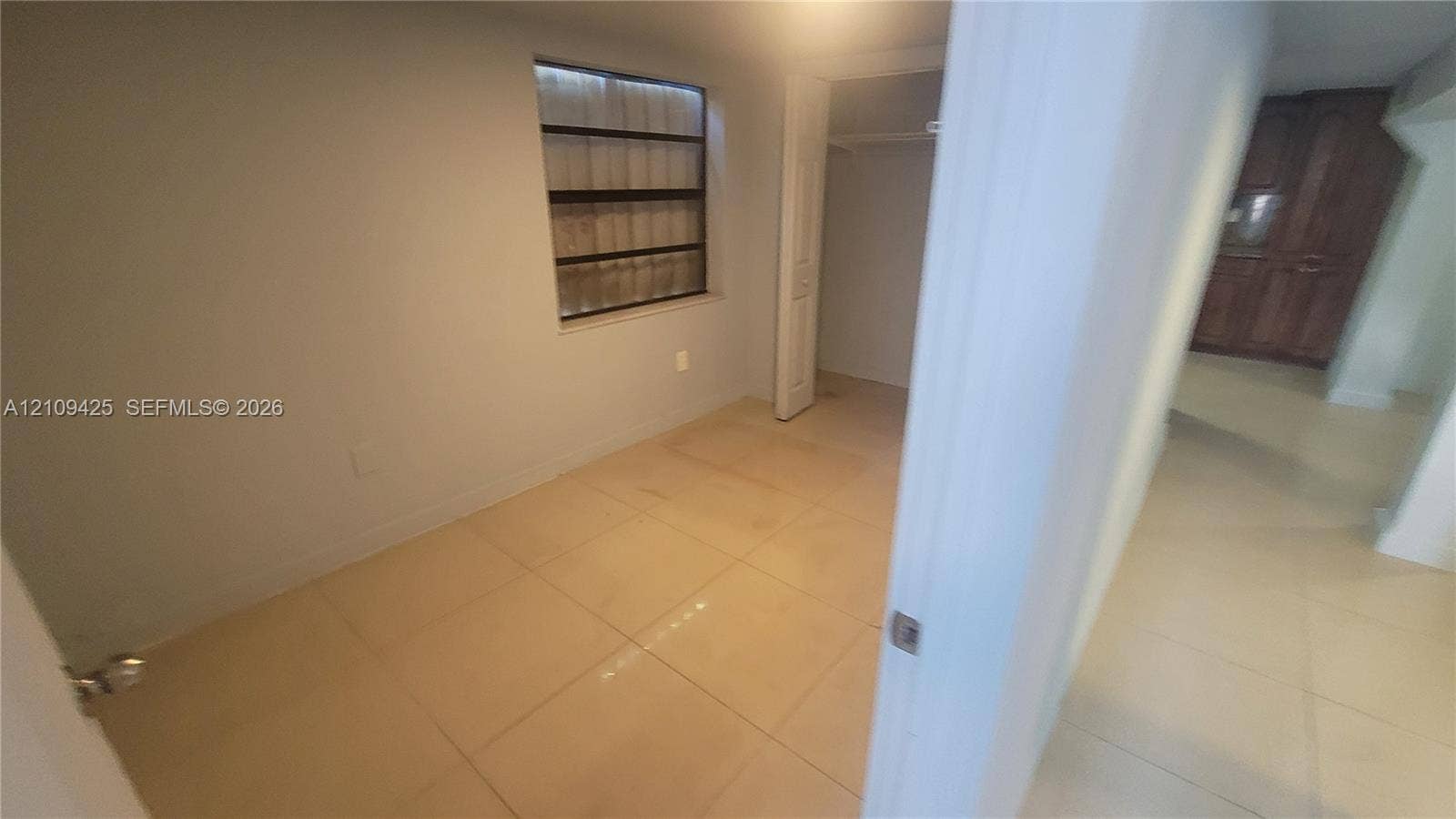 615 NW 25th Court, #B, Miami, Miami, FL 33125 Neutral-toned room featuring large-format tile flooring, a louvered-style window, and a built-in closet with a hinged door