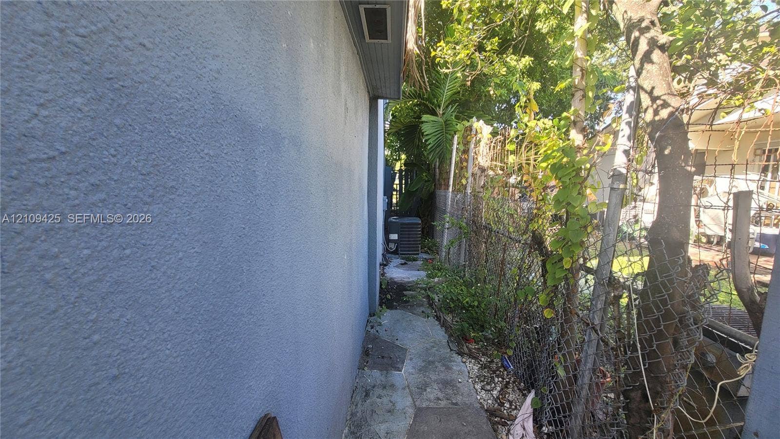 615 NW 25th Court, #B, Miami, Miami, FL 33125 Stucco exterior wall with chain-link perimeter fencing and paved walkway