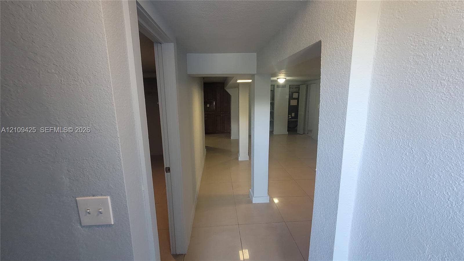 615 NW 25th Court, #B, Miami, Miami, FL 33125 Interior hall featuring neutral-toned large-format tile flooring, textured wall finishes, and a structural support column