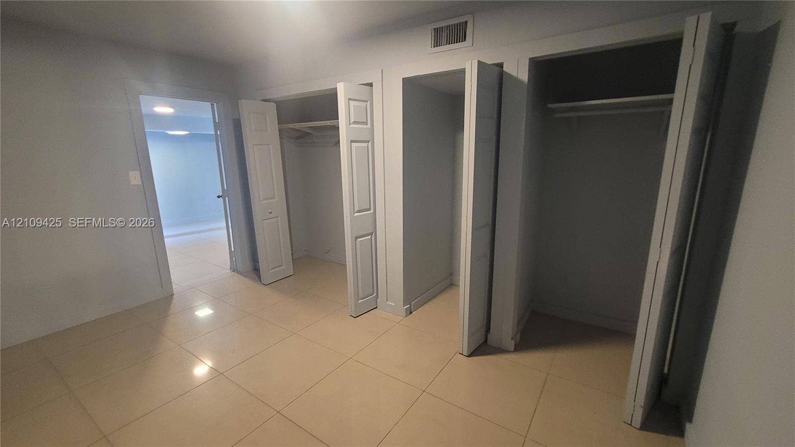 615 NW 25th Court, #B, Miami, Miami, FL 33125 Interior room featuring large-format tile flooring, three white bi-fold closet doors, and built-in shelving