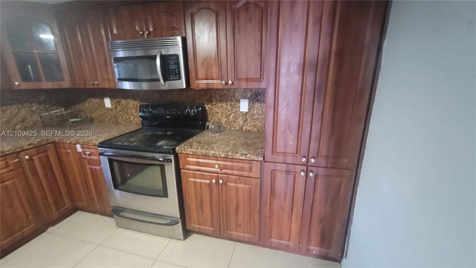 615 NW 25th Court, #B, Miami, Miami, FL 33125 Kitchen featuring wood cabinetry, stone-finish countertops, stainless steel electric range, over-the-range microwave, and tile flooring