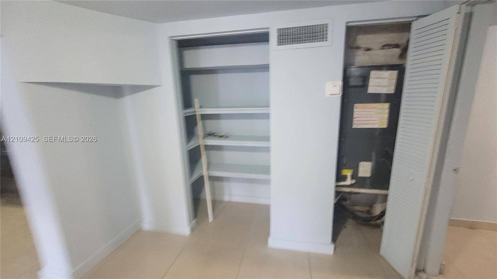 615 NW 25th Court, #B, Miami, Miami, FL 33125 Built-in shelving units and utility closet featuring a mechanical system with louvered door access and tile flooring