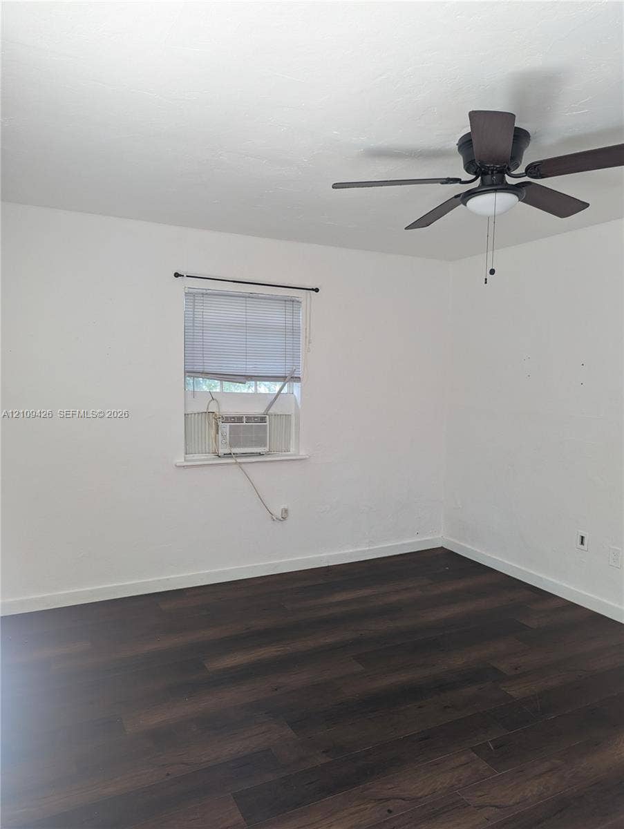 Room featuring wood-finish flooring, white walls, and a ceiling-mounted light fixture with a fan