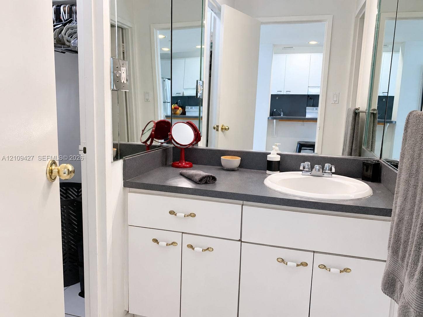 Vanity featuring a solid-surface countertop, integrated basin, dual-handle chrome faucet, and white cabinetry with decorative hardware