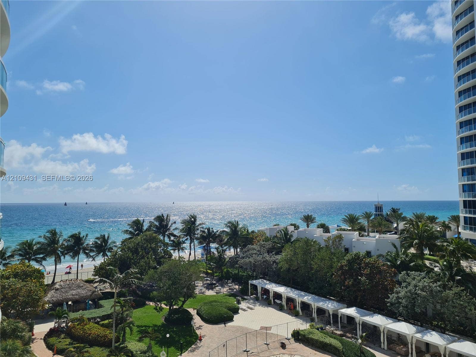 3001 S Ocean Drive, #619, Hollywood, Hollywood, FL 33019 Oceanfront vista featuring mature palm trees, landscaped grounds, a paved courtyard, and covered white structural walkways