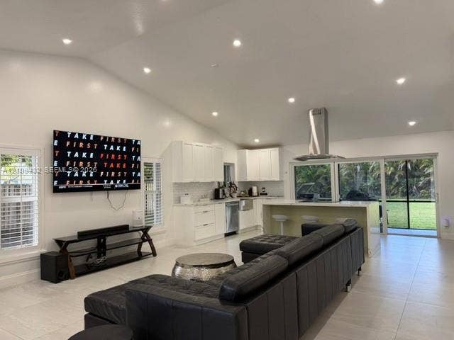 254 NW 107th Terrace, Coral Springs, FL 33071 Open-concept kitchen and living area featuring high vaulted ceilings, recessed lighting, white shaker-style cabinetry, a central island with an integrated stainless steel range hood, and sliding glass doors