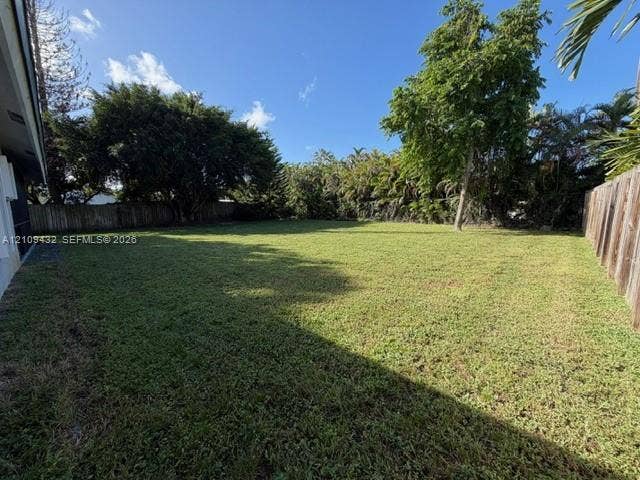 254 NW 107th Terrace, Coral Springs, FL 33071 Expansive backyard featuring a large grass lawn, perimeter wood fencing, and mature trees