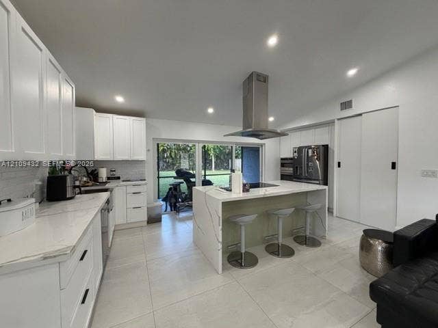 254 NW 107th Terrace, Coral Springs, FL 33071 Kitchen featuring white cabinetry, waterfall-edge island with stone-finish countertop, stainless steel vent hood, recessed lighting, and large-format tile flooring