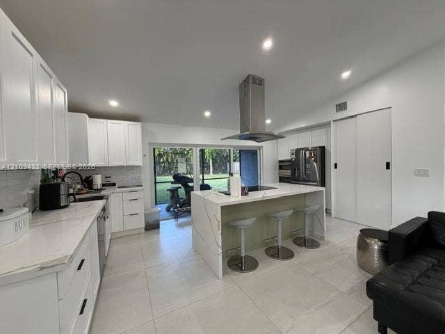 254 NW 107th Terrace, Coral Springs, FL 33071 Kitchen featuring a center island with a waterfall countertop, white shaker-style cabinetry, a stainless steel range hood, stone-finish flooring, and sliding glass doors
