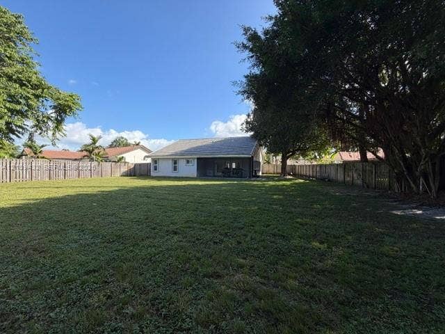 254 NW 107th Terrace, Coral Springs, FL 33071 Expansive backyard featuring a large grass lawn, mature trees, and perimeter wood fencing
