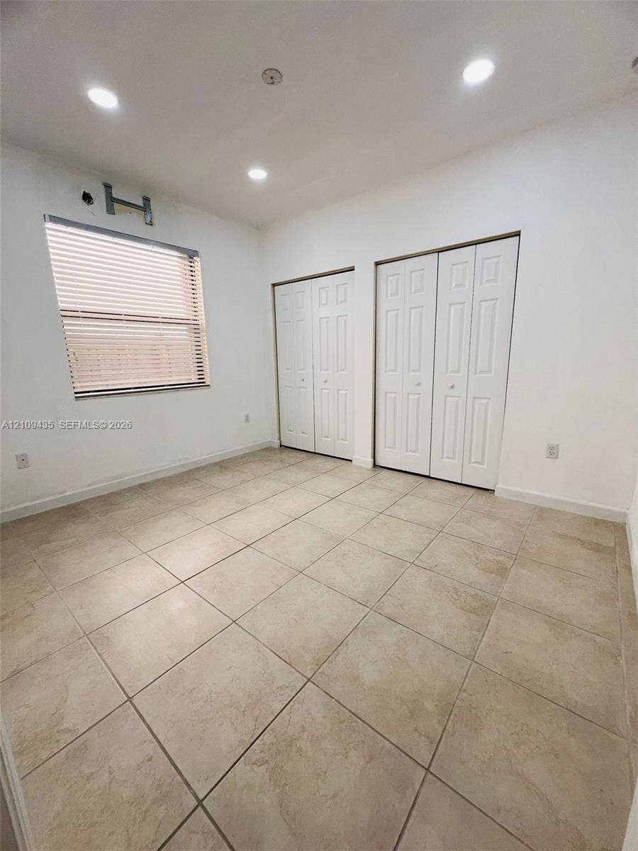 24161 SW 115th Court, #1, Homestead, Homestead, FL 33032 Room featuring neutral tile flooring, recessed ceiling lighting, two bi-fold closets, and a window with horizontal blinds