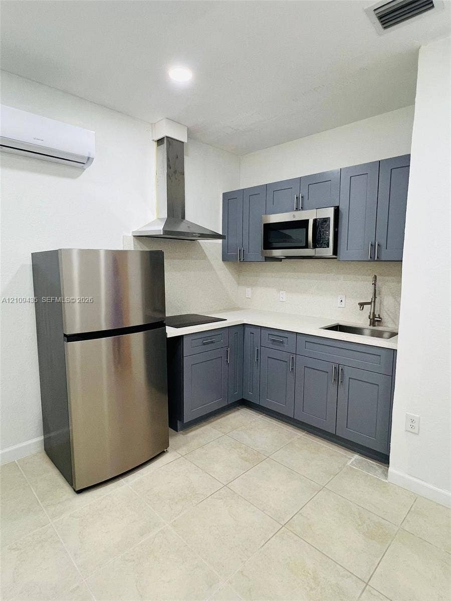 24161 SW 115th Court, #1, Homestead, Homestead, FL 33032 Kitchen featuring grey shaker-style cabinetry, solid-surface countertops, stainless steel appliances, a chimney-style range hood, and tile flooring
