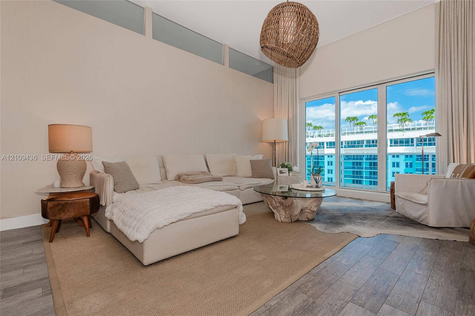 High ceilings featuring clerestory windows, wood-finish flooring, and large-format sliding glass doors with balcony access