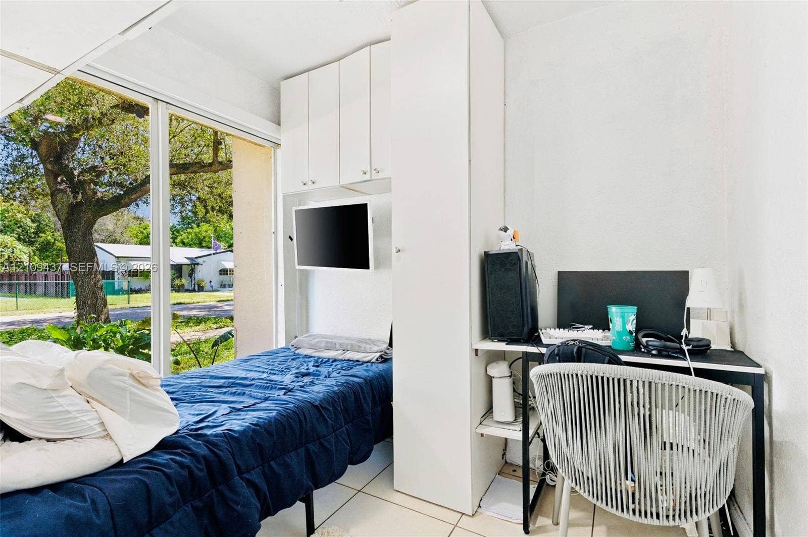 Floor-to-ceiling windows, white tile flooring, and custom built-in white cabinetry with integrated storage