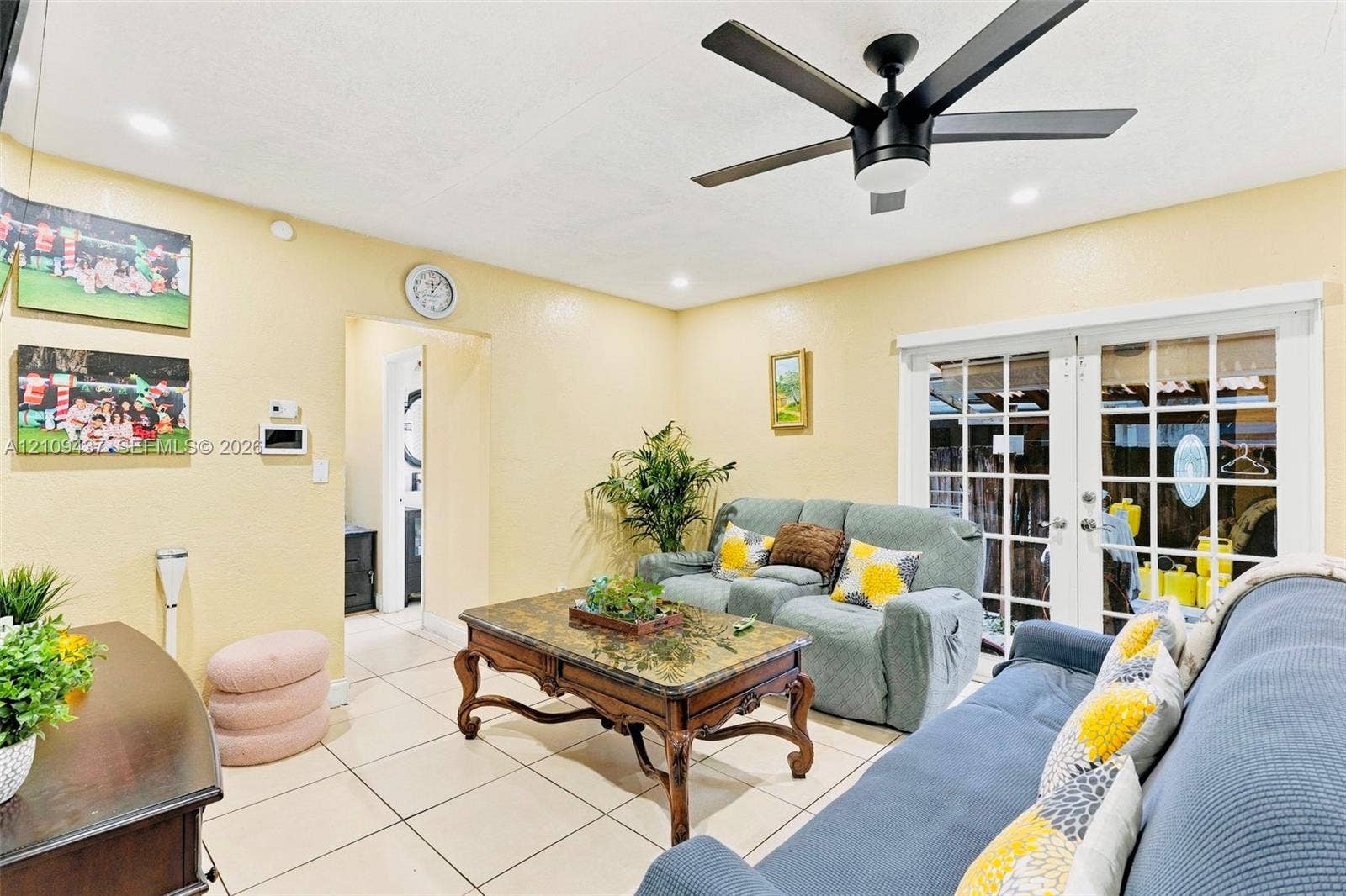 Large-format ceramic floor tile, matte black ceiling fan, and white French doors featuring a multi-pane glass design