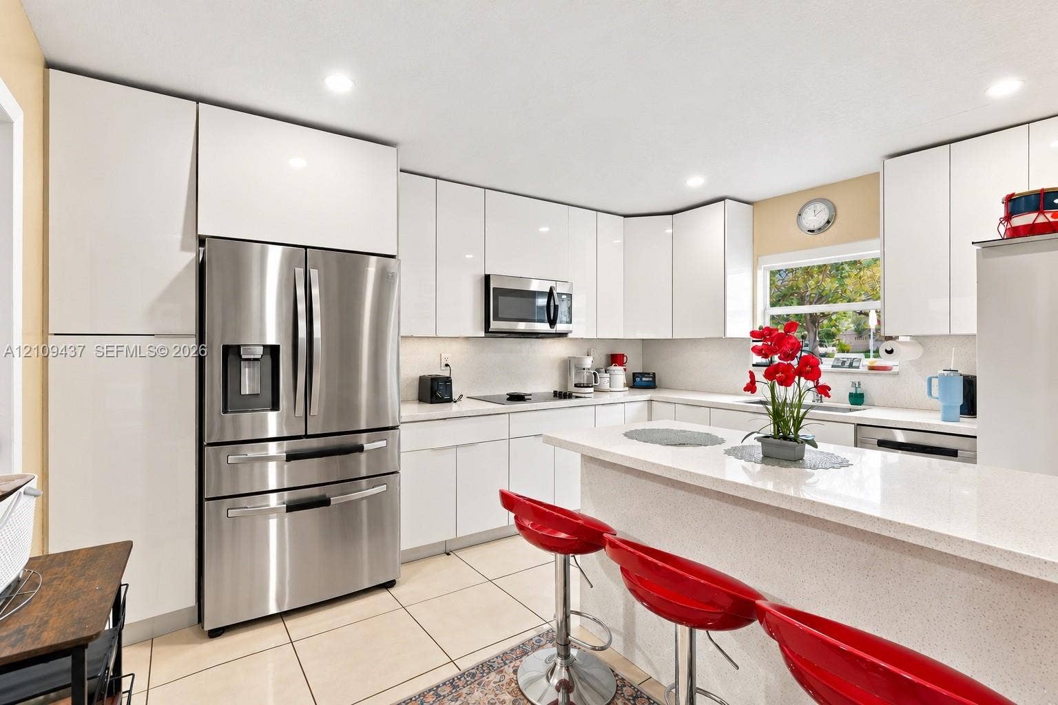 Kitchen featuring high-gloss white cabinetry, solid surface countertops, stainless steel appliances, recessed lighting, and tile flooring
