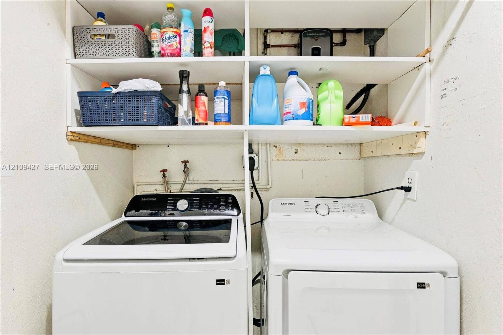 Laundry area featuring built-in white shelving and a side-by-side washer and dryer set