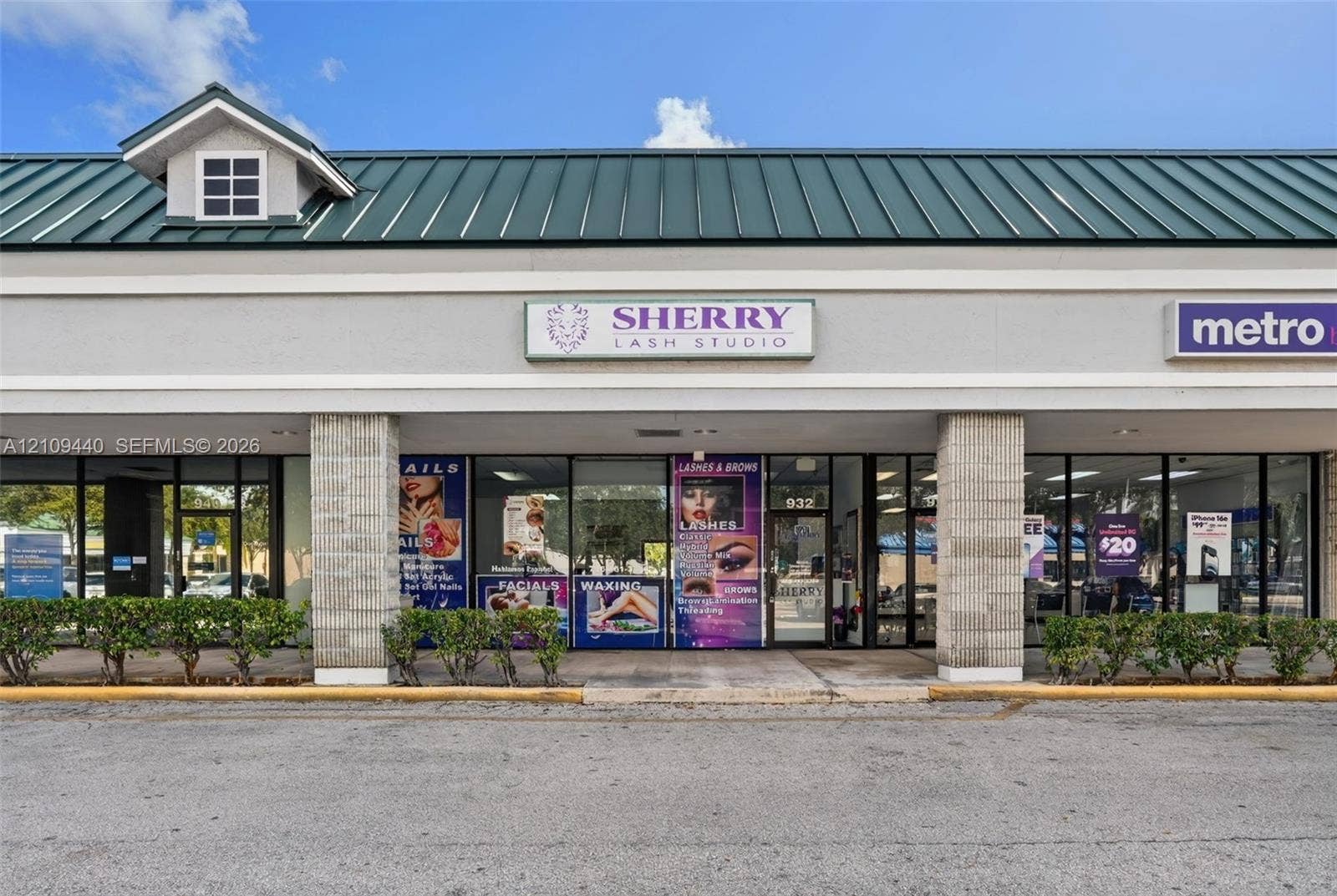 Commercial storefront featuring a green metal gable roof, grey masonry facade, expansive glass-pane storefront windows, and dedicated exterior signage space