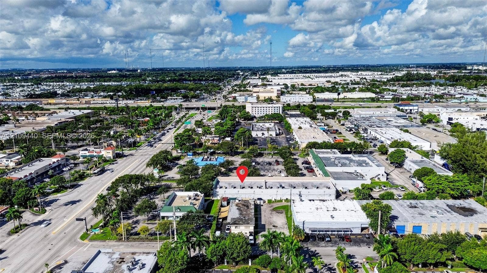 Aerial perspective of commercial property featuring proximity to major thoroughfares, surface parking, established landscaping, and urban infrastructure