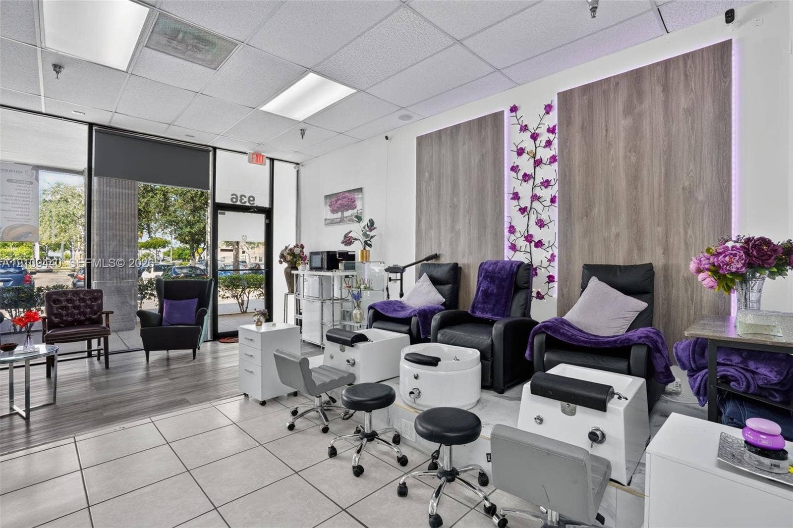 Commercial space featuring full-height storefront glass, neutral tile flooring, wood-finish wall paneling, and integrated ambient lighting