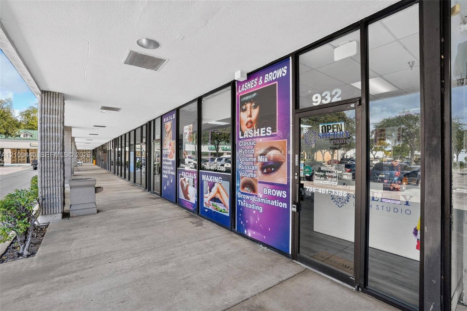 Commercial storefront featuring a full-height glass facade with aluminum framing, concrete walkway, and recessed ceiling lighting