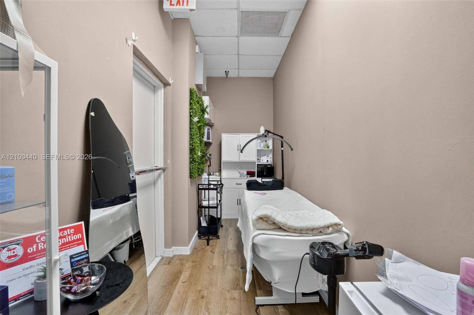 Enclosed interior space featuring wood-finish flooring, white built-in cabinetry, and a drop ceiling