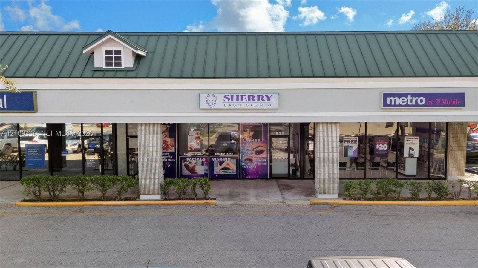 Commercial storefront featuring a green metal gable roof, expansive glass frontage, and stone-faced support columns